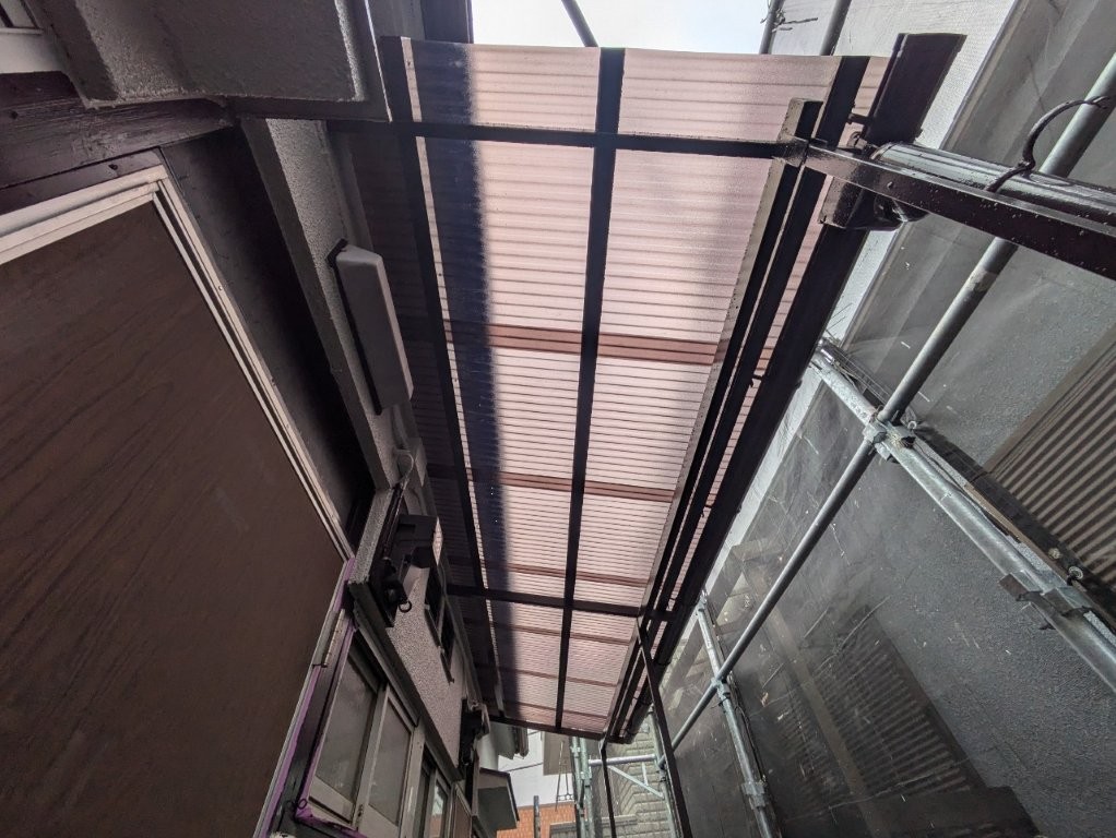 アパートの通路から見上げた新設波板の裏側。光を透過するポリカ材で明るい仕上がりに