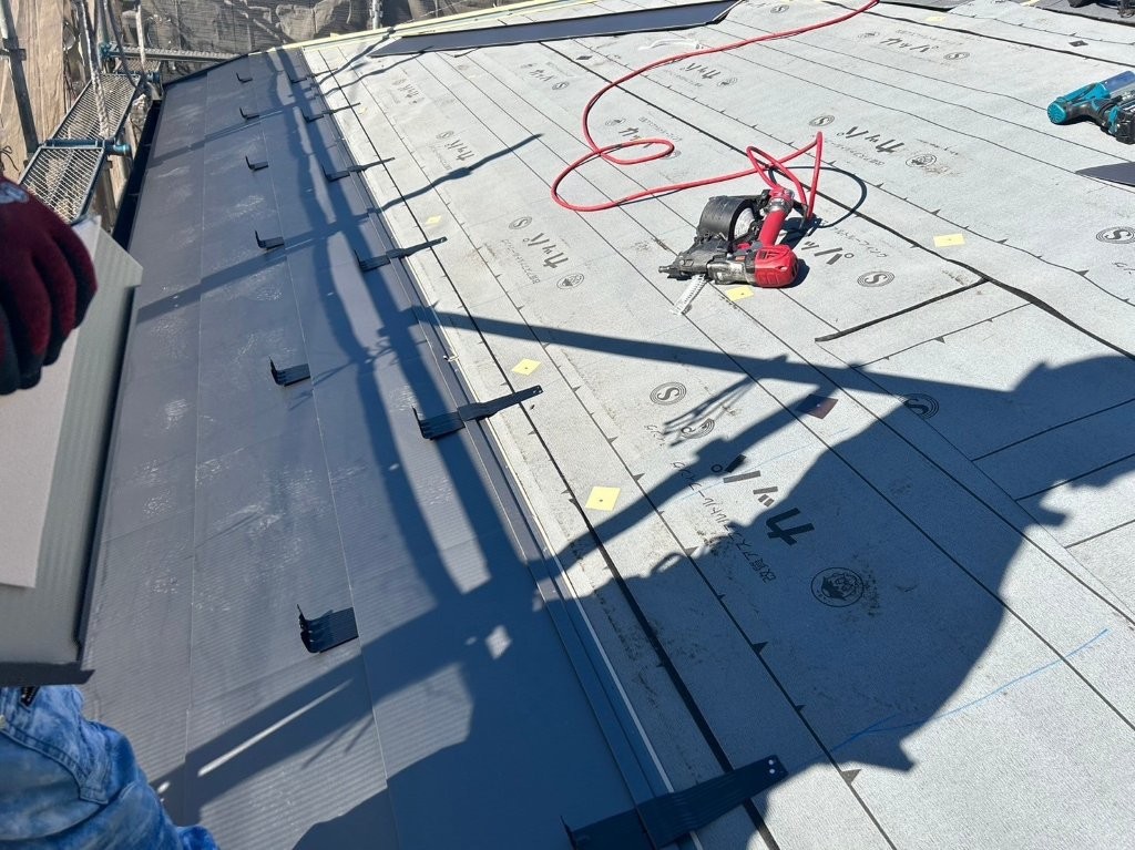 加須市アパート屋根にガルバリウム鋼板を施工し雪止め金具を設置している様子
